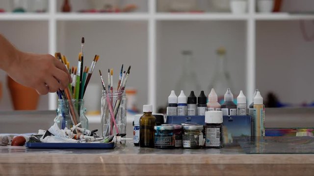 Hand chosing brushes and colors to paint