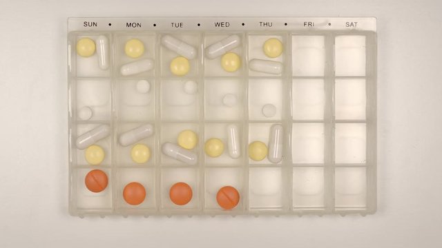 TOP VIEW: Pills fill a plastic organizer - Stop motion