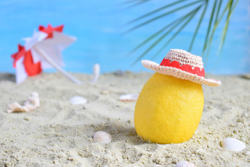 Creative minimal summer idea. Lemon citrus hipster in bamboo hat and beach umbrella on sand. Tropical beach concept. Creative art. Copy space