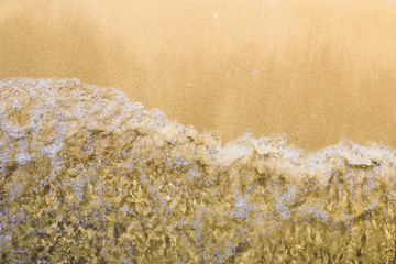 Summer beach pattern - wave on a sandy beach, top view, close-up, copy space