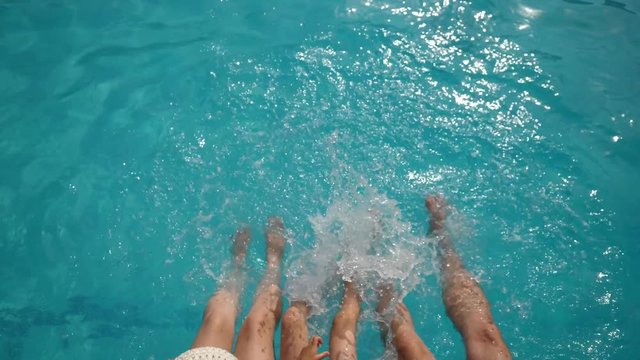 Child and parents feet playing in blue water, summer of joy
