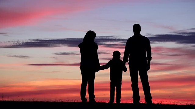 Family silhouettes portrait at sunset, parent and child hold hands, invincible team