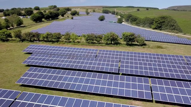 4k aerial drone view flying low over rows of solar panels at a solar power generation plant