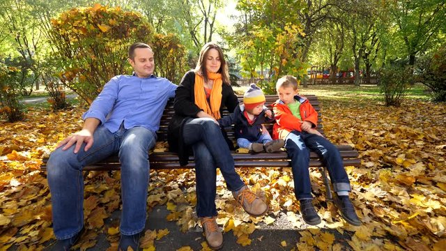 Portrait of family with two children sitting on a bench in beautiful autumn park