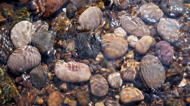 Sunlit Pebbles in a Stream.

Pebbles in a shallow stream dappled by sunlight caused by ripples.