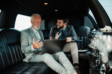 Senior businessman and his assistant sitting in limousine and celebrating their job success. - obrazy, fototapety, plakaty