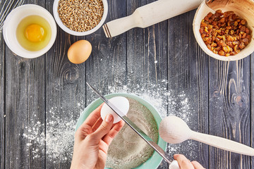 Hands working with dough preparation recipe bread, pizza or pie making ingridients, food flat lay on kitchen table background. Braking an egg