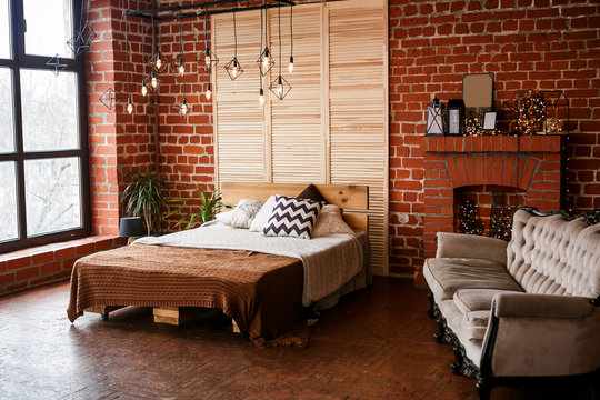 Simple bedroom with double bed, red brick wall and big window