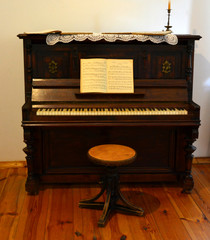 ancient musical instrument, a vintage piano with notes, a candle and a chair.