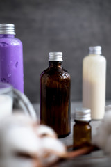 Bottles with natural spa cosmetic products on dark gray concrete table. Beauty blogger, salon treatments, minimalism concept