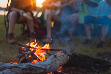 Friends group travel summer camping fire together in forest with backpack and tent picnic drinks...