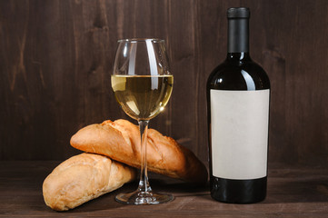 white wine composition with bread bottle and wineglass on wooden background