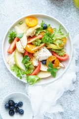 Original panzanella salad with mozarella, toasted baguette, tomatoes and plums on rustic background. Summer cuisine concept. Top view