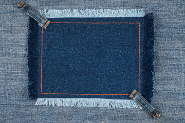 Frame with fringe and with two straps jeans, lies on the blue denim, with space for your text.