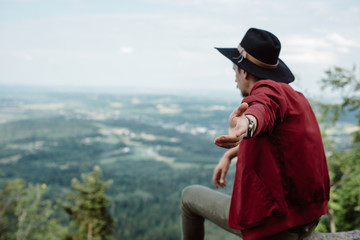 Man traveler sitting on a stone on the background of nature