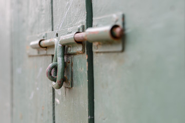 Close-up old bolt steel on green wooden doors