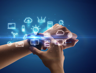 Close up female hand with smartwatch and multimedia symbols around and blue background
