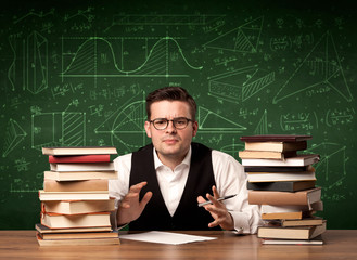 A young passionate male teacher sitting at school desk, reading a book, with area algorythm...