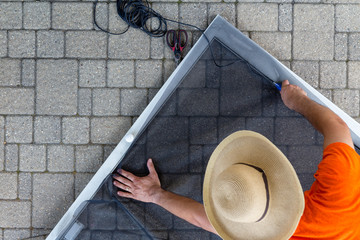 Man wearing hat repairing old patio door - 214366031