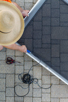 Man Repairing A Damaged Screen Door On A Patio