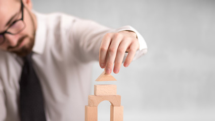 Young handsome businessman using wooden building blocks 