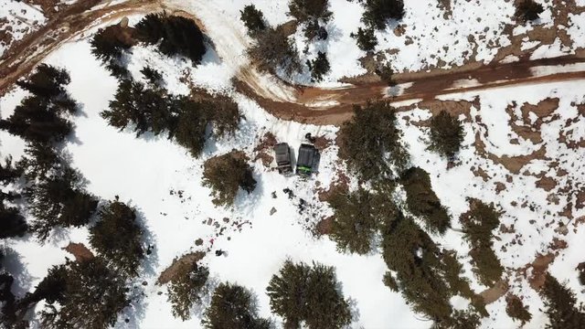 Drone gains altitude above UTV riders on a snowy trail
