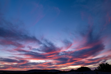 Wispy colorful clouds of sunset over hills of sand in the desert