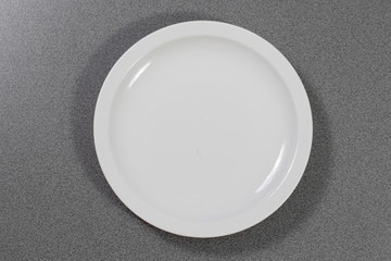 Weißer Teller aus Porzellan auf einem grauen Holztisch 