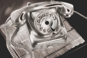 An ancient silver dial disk phone in futuristic processing on on the table on a stand dark...