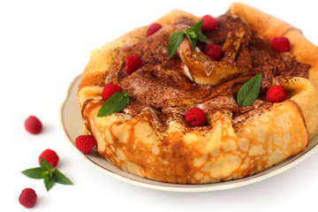 Round pancakes are placed in a heap. It is decorated in the form of a cake. The dish is decorated with whipped cream, fresh raspberries and a sprig of mint. Pancakes are the main dish of Maslenitsa.