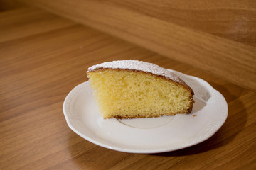 Slice of a delicious cake with powdered sugar on a white plate