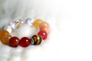Tiger eye and various quartz lucky stone bracelet in red and white tone on white wool texture background and have some space for write wording
