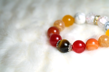 Tiger eye and various quartz lucky stone bracelet in red and white tone on white wool texture background and have some space for write wording
