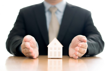 Business man hand hold the house model saving small house.