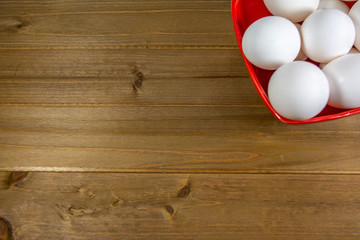 A group of eggs inside a deep red bowl waiting for the chef to use them in a meal