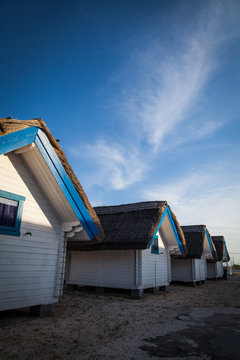 Row of blue and white painted huts in a sea resort.