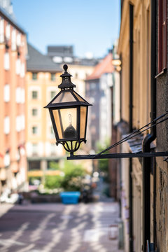 City view of a old vintage street light mounted on a exterior wall in Stockholm Sweden.