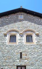 Fototapeta na wymiar Window on a stone wall of the house. Due to the windows location, facade looks like a human face
