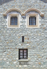 Window on a stone wall of the house. Due to the windows location, facade looks like a human face