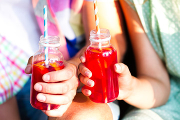 Picnic theme: happy young family  holding drinks, toast bottle with red juice , close-up