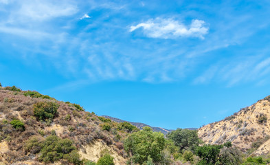 Fototapeta na wymiar Blue sky and white clouds form a bowl in center of Southern California mountains on summer day