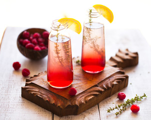 Summer refreshing non-alcoholic cocktails. Fruit drinks. Raspberry homemade lemonade with fresh organic rosemary and lemon. On a white wooden table.