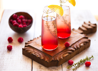 Summer refreshing non-alcoholic cocktails. Fruit drinks. Raspberry homemade lemonade with fresh organic rosemary and lemon. On a white wooden table.