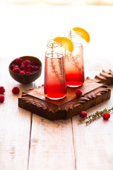 Summer refreshing non-alcoholic cocktails. Fruit drinks. Raspberry homemade lemonade with fresh organic rosemary and lemon. On a white wooden table.