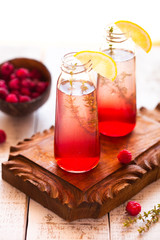 Summer refreshing non-alcoholic cocktails. Fruit drinks. Raspberry homemade lemonade with fresh organic rosemary and lemon. On a white wooden table.
