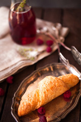 Golden fresh croissant on old wooden background close up with raspberry