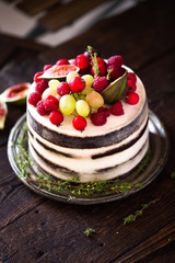Delicious chocolate cake with figs and berries on a rustic background. Wedding Naked cake with fruits in rustic style.