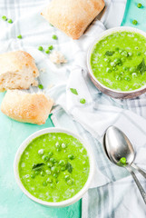 Green pea soup with fresh bread on light blue concrete table, copy space