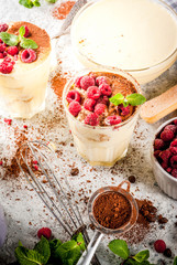 Cooking Italian food dessert Tiramisu, with all the necessary ingredients cocoa, coffee, mascarpone cheese, mint and raspberries, on grey stone background.  Copy space