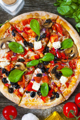 Homemade pizza with tomatoes, mozzarella and basil. Top view with copy space on wooden table.